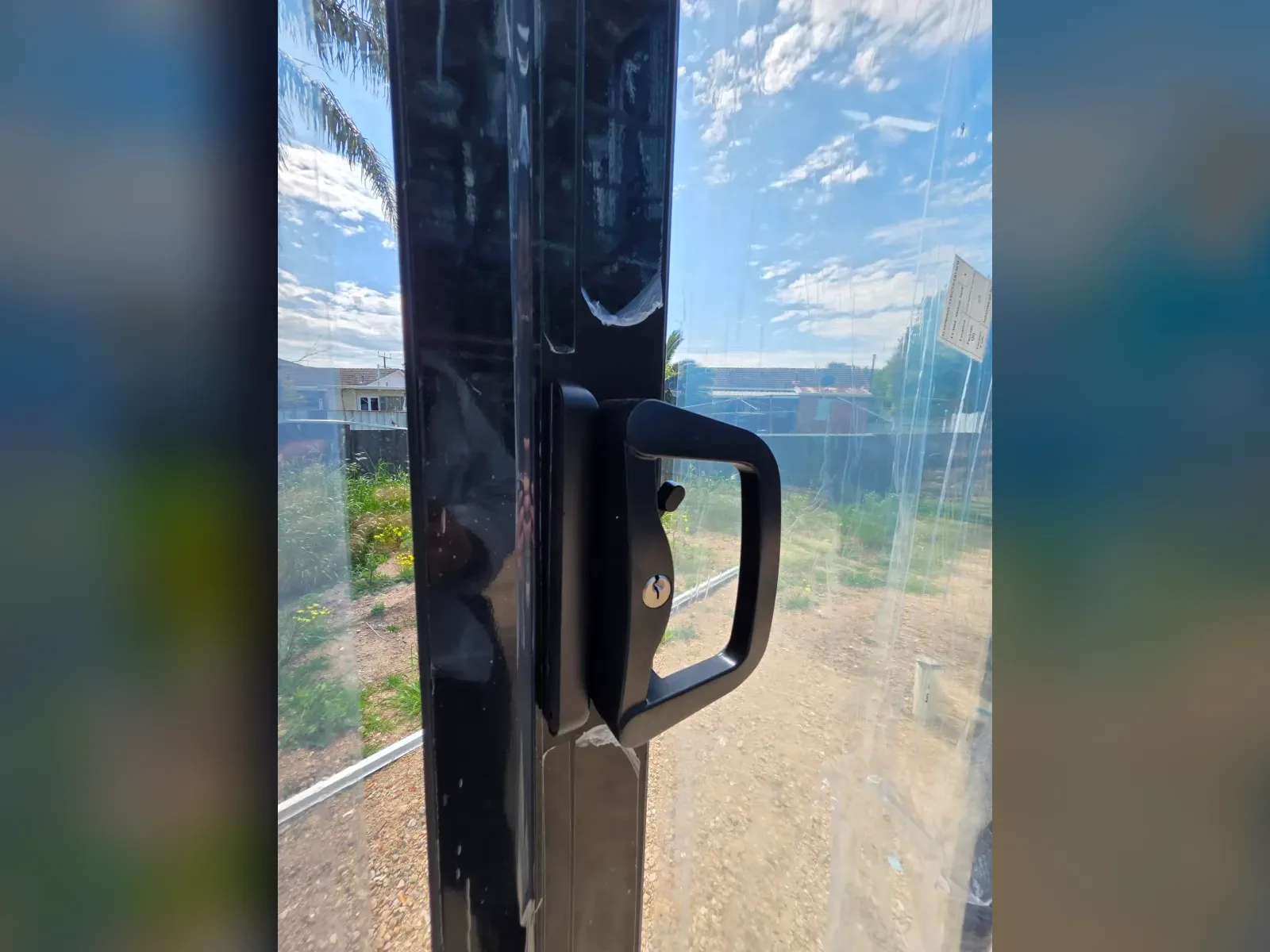 Close-up of the black handle and lock hardware on an installed aluminium sliding door