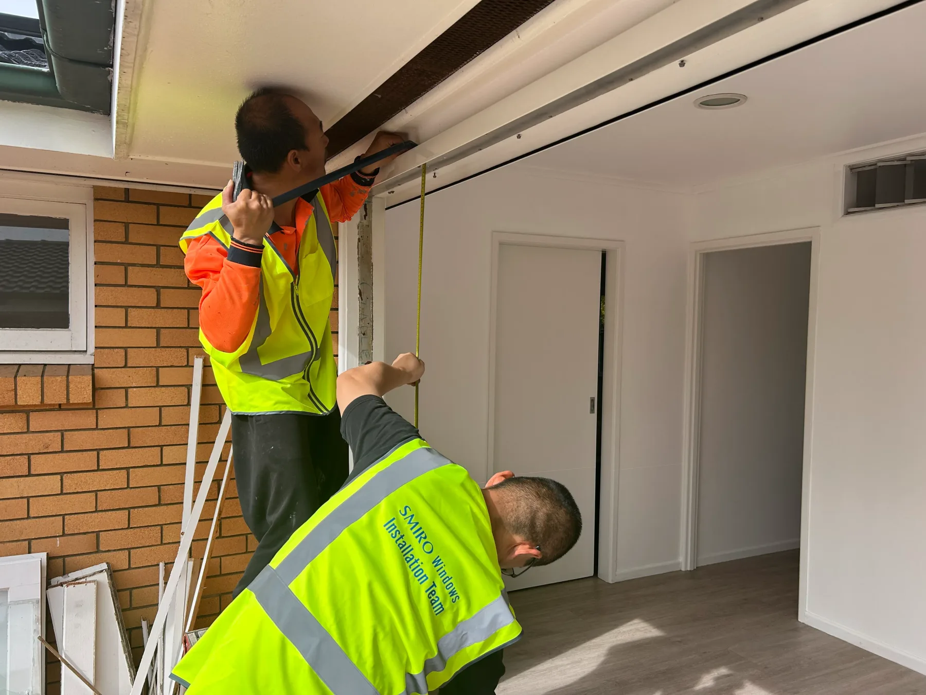 SMIRO installers measuring a door opening before fitting a new sliding door in Kenmore QLD